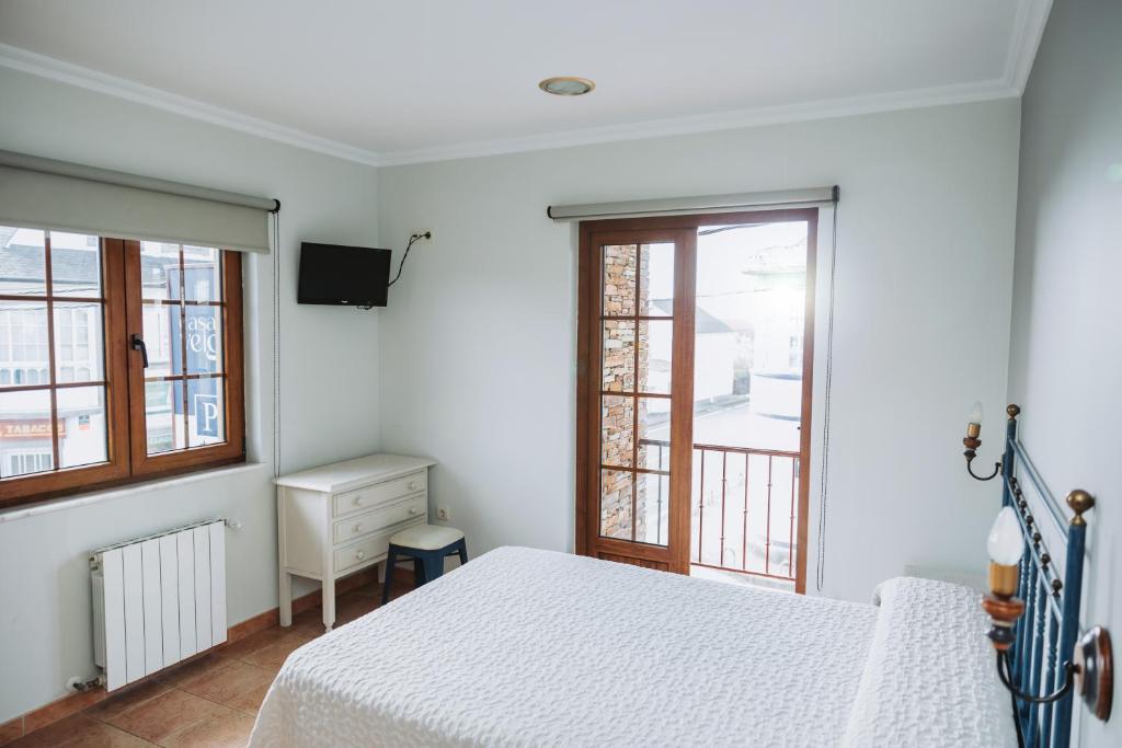 a white bedroom with a bed and a window at Casa Veiga Rooms in Valdoviño