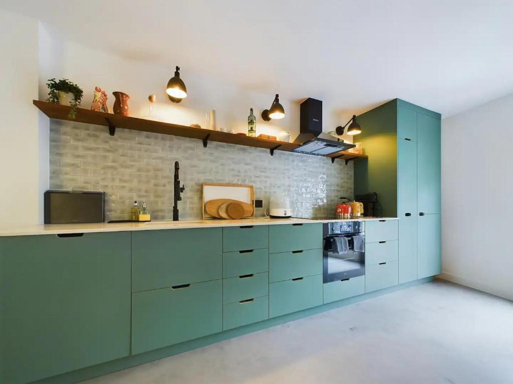 a kitchen with blue cabinets and a brick wall at Pass the Keys Stylish and Modern 2Bed 2Bath Hackney Apartment in London