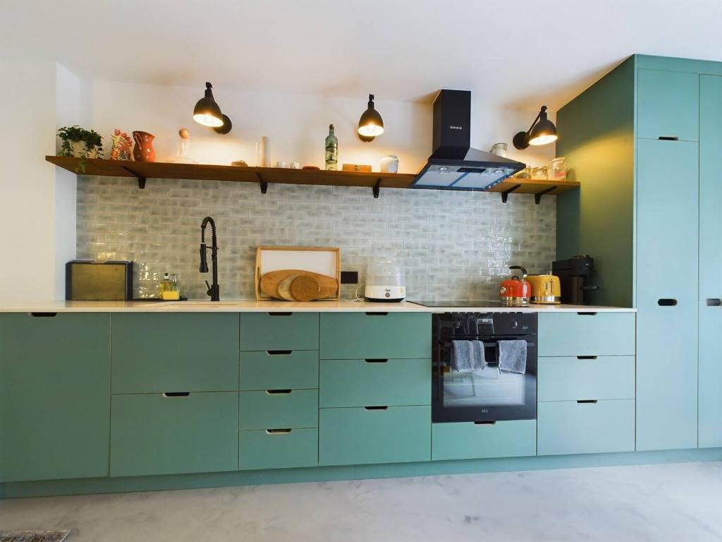 a kitchen with blue cabinets and a brick wall at Pass the Keys Stylish and Modern 2Bed 2Bath Hackney Apartment in London