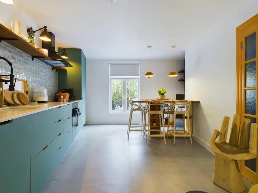 a kitchen with blue cabinets and a table with chairs at Pass the Keys Stylish and Modern 2Bed 2Bath Hackney Apartment in London