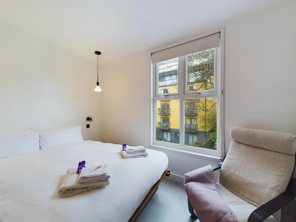 a bedroom with a bed and a chair and a window at Pass the Keys Stylish and Modern 2Bed 2Bath Hackney Apartment in London