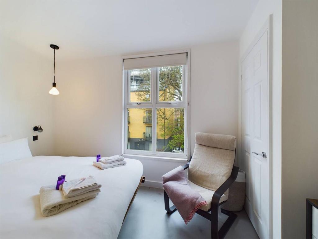a bedroom with a bed and a chair and a window at Pass the Keys Stylish and Modern 2Bed 2Bath Hackney Apartment in London