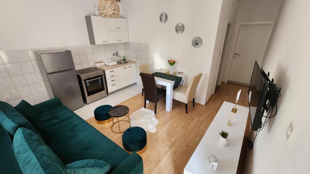 a living room with a green couch and a kitchen at Apartman SunShine in Trebinje