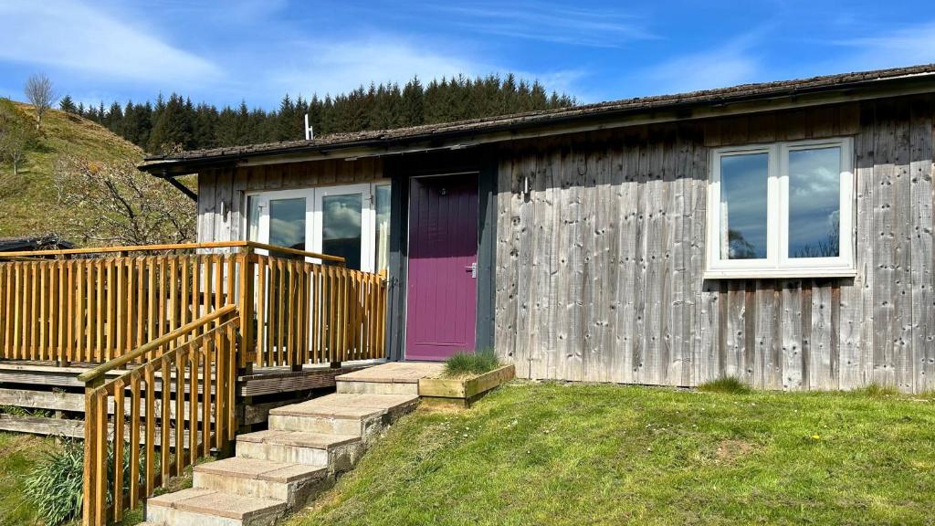 een klein houten huisje met een paarse deur en trap bij Skye in Oban