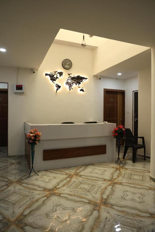 un hall avec une horloge sur le mur et des fleurs dans l'établissement Hotel Aaram Kalupur, à Ahmedabad