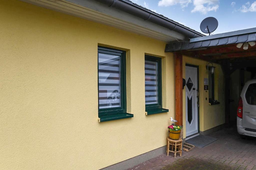 a yellow house with green windows and a door at Ferienwohnung Küstenstübchen Gruse in Bartenshagen-Parkentin