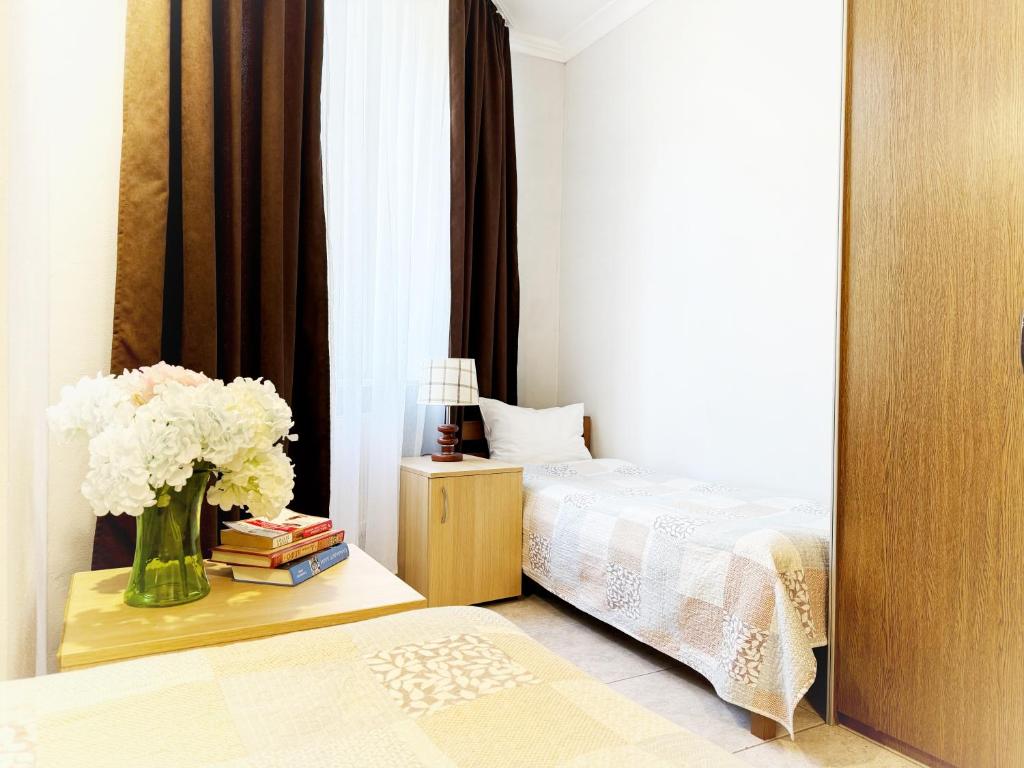 1 dormitorio con 1 cama y un jarrón de flores sobre una mesa en SIGNEEV'S Villa, en Kiev