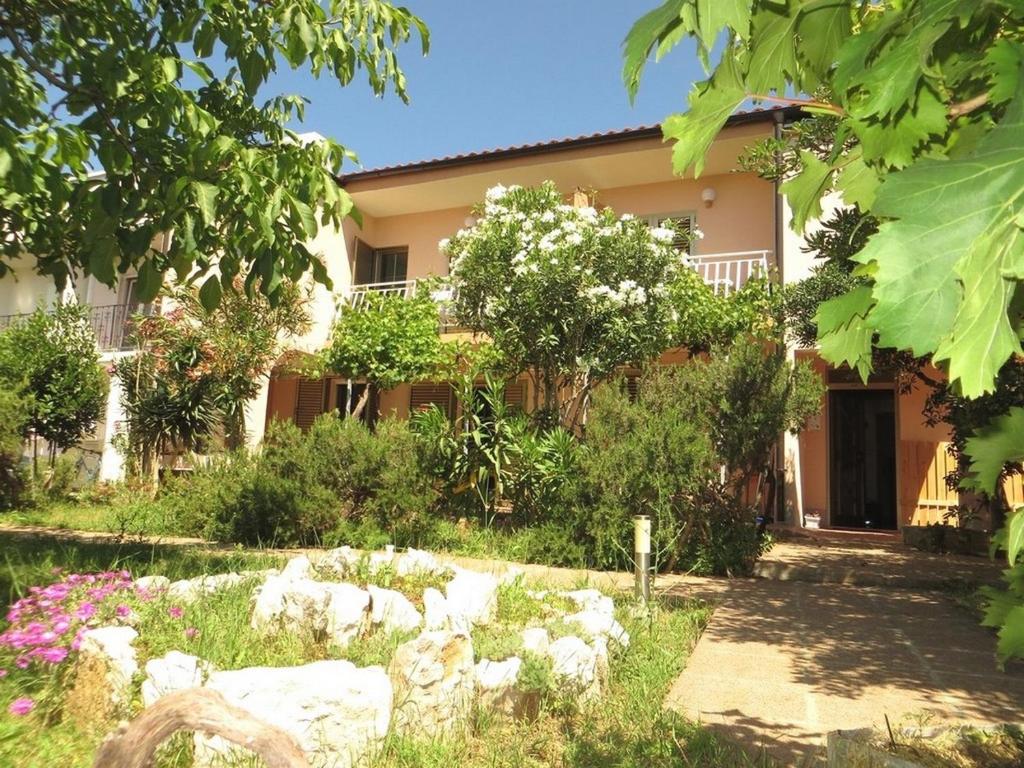 a house with a garden in front of it at Apartment and rooms Kristina in Baška