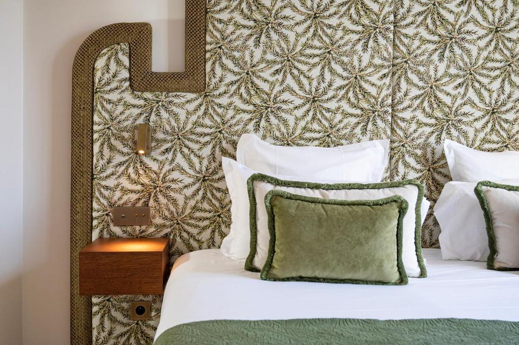 una camera da letto con un letto con cuscini bianchi di Lou Cagnard a Saint-Tropez