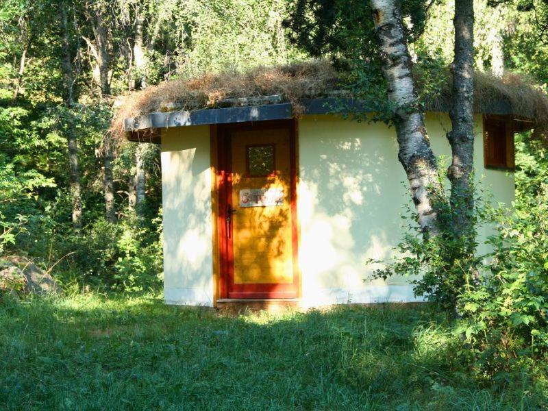 une petite maison avec un toit de chaume dans l'herbe dans l'établissement Les jardins de l'Orri, à Planès