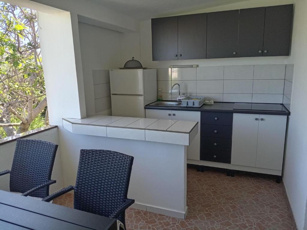 a kitchen with a counter and two chairs in it at Apartments Šešo in Pag