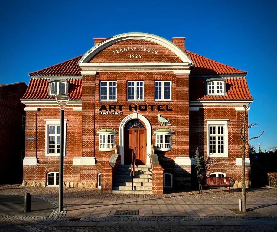 ein rotes Backsteingebäude mit einem Kunsthotel darauf in der Unterkunft ART Hotel Dalgas in Brande