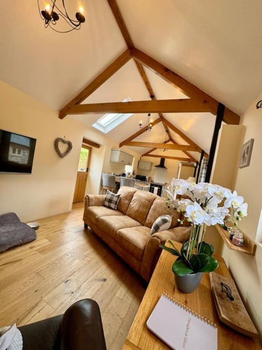a living room with a couch and a table with flowers at Dog friendly barn conversion in the Wye Valley in Mitchel Troy