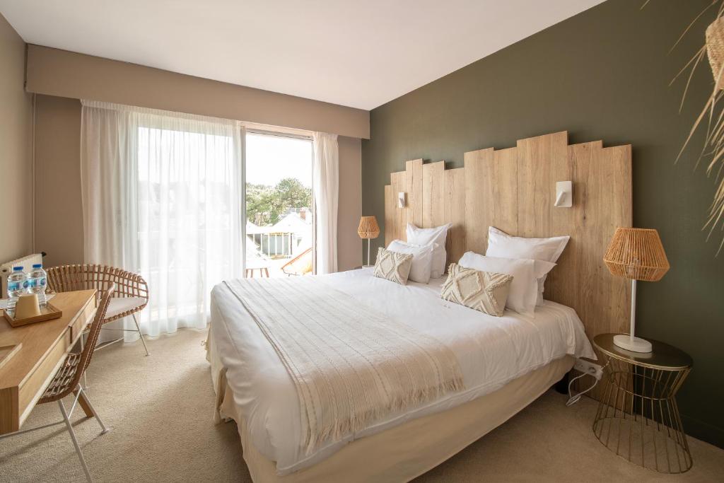 um quarto com uma cama grande e uma secretária em Hôtel BO & MIA em La Baule