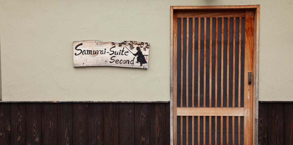 Samurai Suite 2 , 15mins from Kyoto Eki , 5 mins to Arashiyama في كيوتو: لوحة على جانب مبنى مجاور لباب