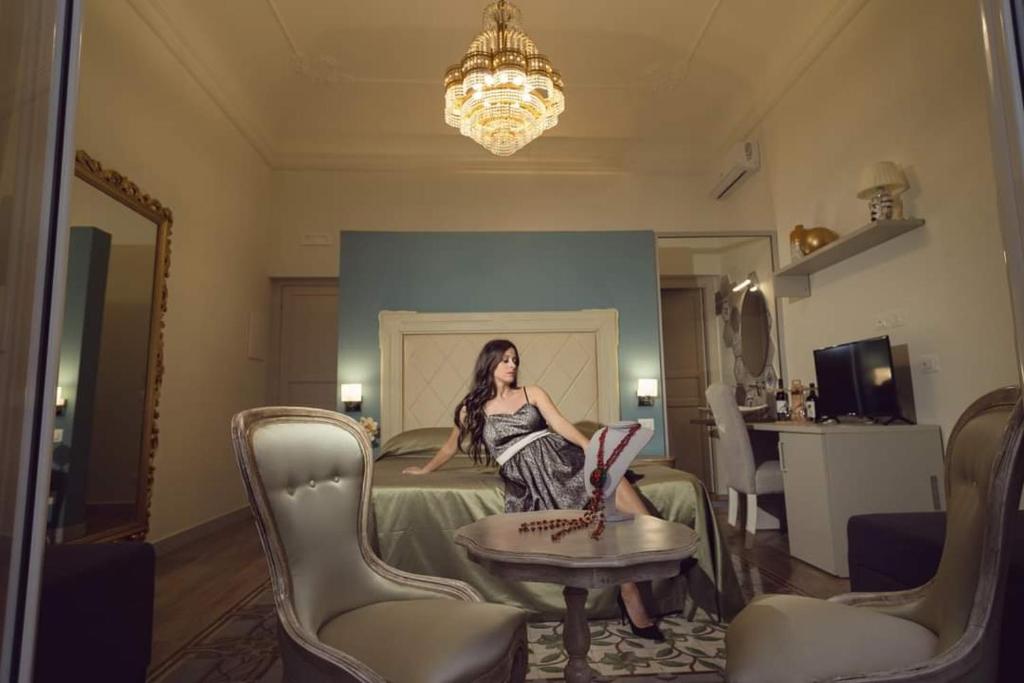 Kèramos Luxury Rooms في شاكا: امرأة تجلس على سرير في غرفة