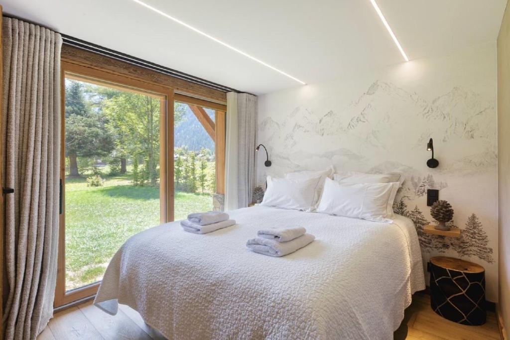 - une chambre avec un lit blanc et des serviettes dans l'établissement Chalet Contemporain pour 12 personnes avec Sauna, à Vernaison