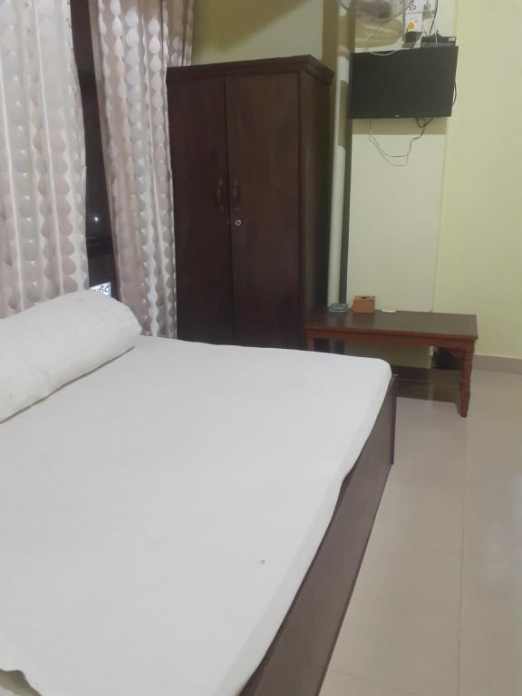 Om siddhababa Restaurant and Lodge في بهاراتبور: غرفة نوم بسرير أبيض وخزانة خشبية