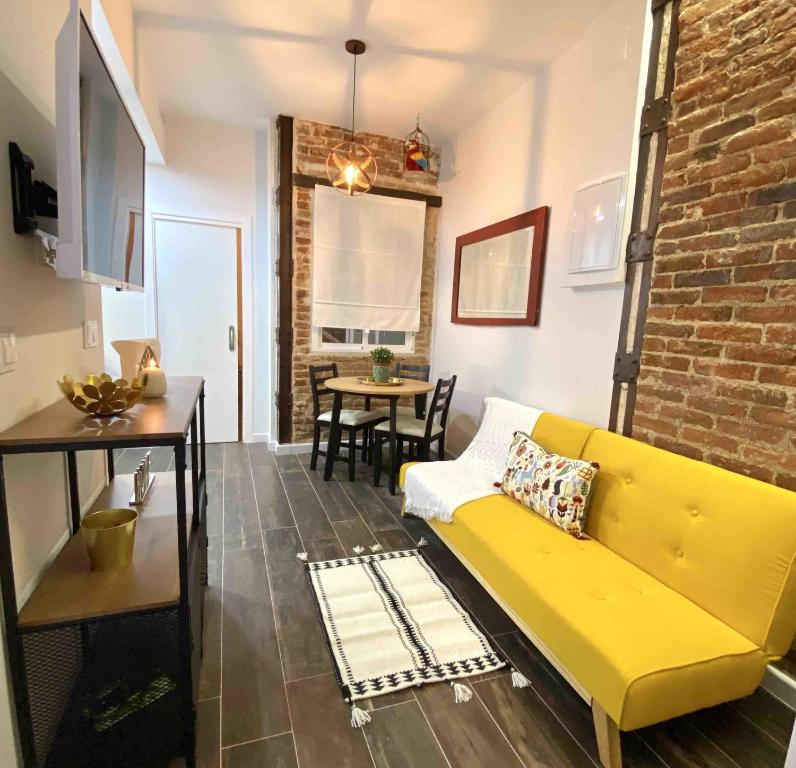 a living room with a yellow couch and a brick wall at Gilber apartment sleep 3 in London