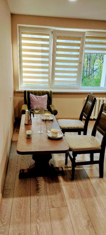a dining room with a table and chairs and windows at Apartamentai Auris in Druskininkai