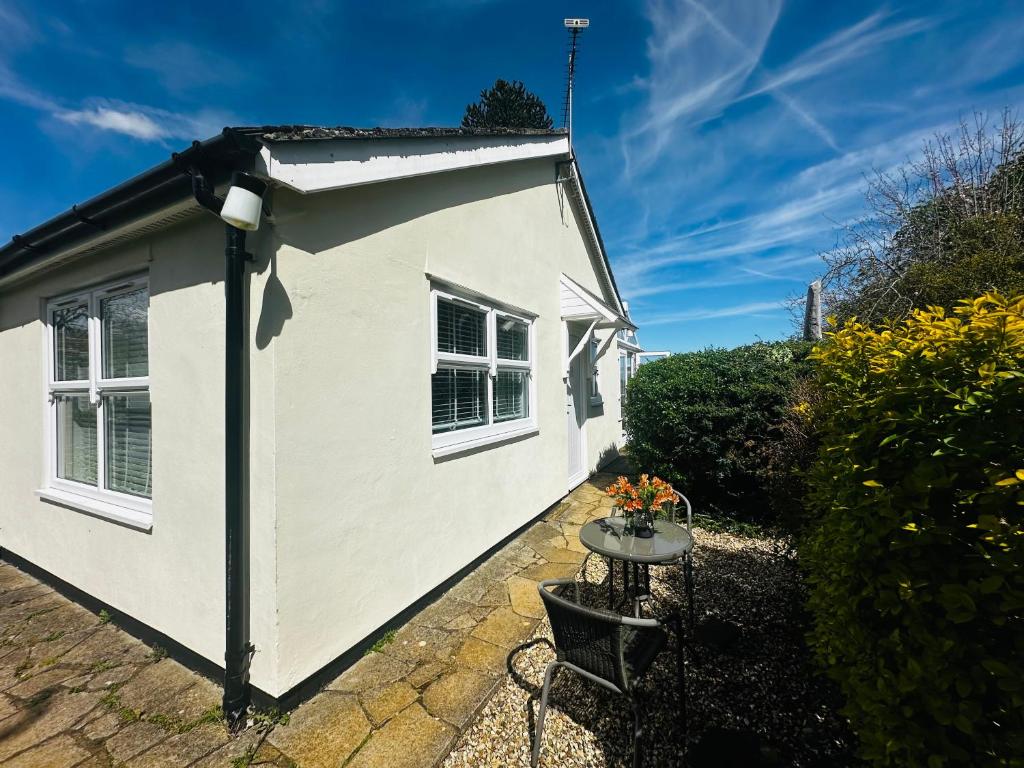 a white cottage with a table in the garden at Cherry Bungalow Guesthouse in Shrivenham