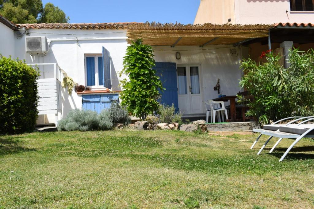 uma pequena casa branca com uma porta azul em Sa Domitta di Suiles em Olbia