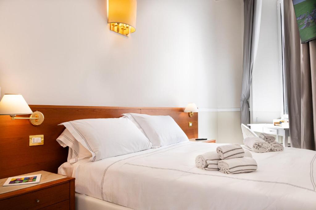 een slaapkamer met een wit bed en handdoeken bij Hotel Domus Rome in Rome