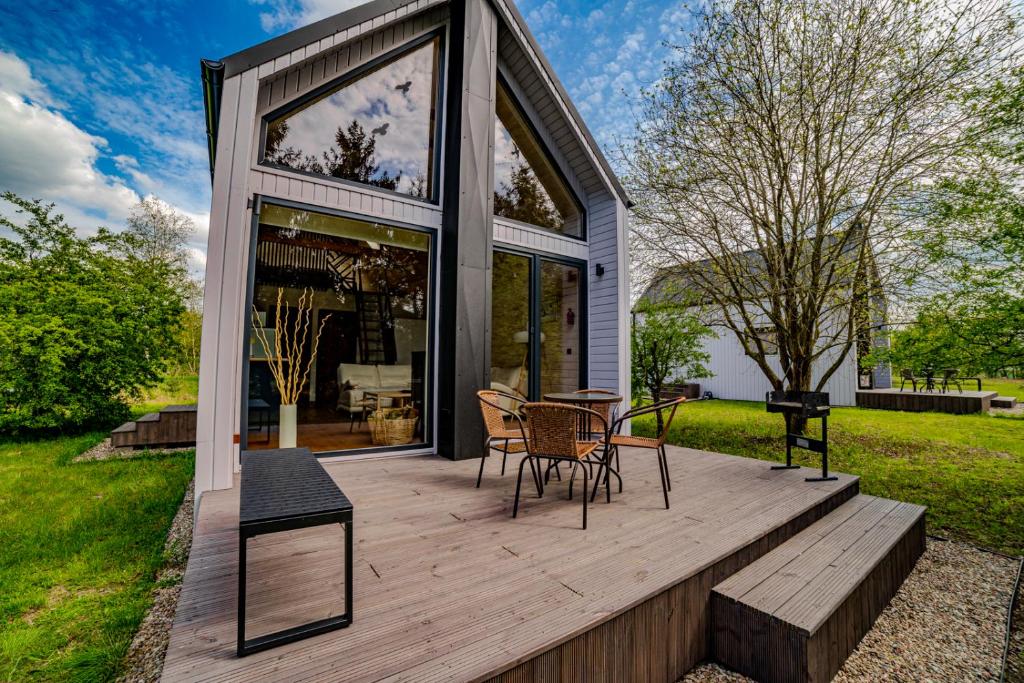 una terrazza in legno con tavolo e sedie. di POCZUJ NATURĘ - domki nad jeziorem a Stare Wierzchowo