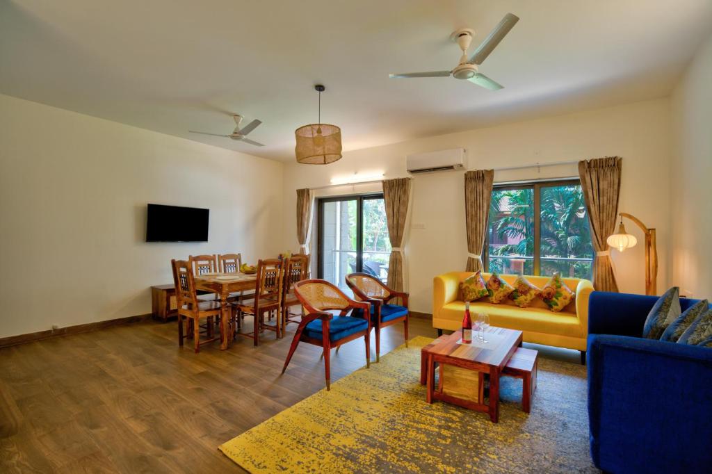 a living room with a couch and a table and chairs at Lavish 2BHK Apartment with Swimming Pool in Candolim in Candolim