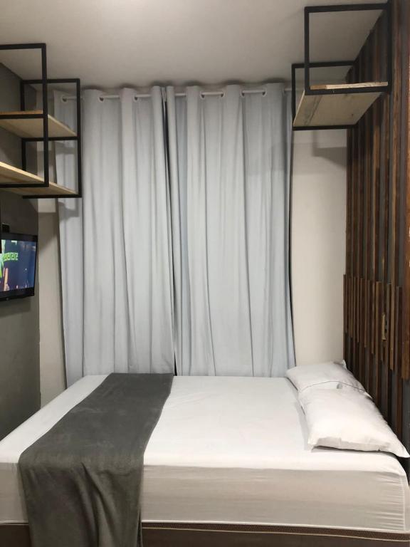- une chambre avec un lit doté de draps blancs et une fenêtre dans l'établissement Lofts Paraíso, à Luís Eduardo Magalhães