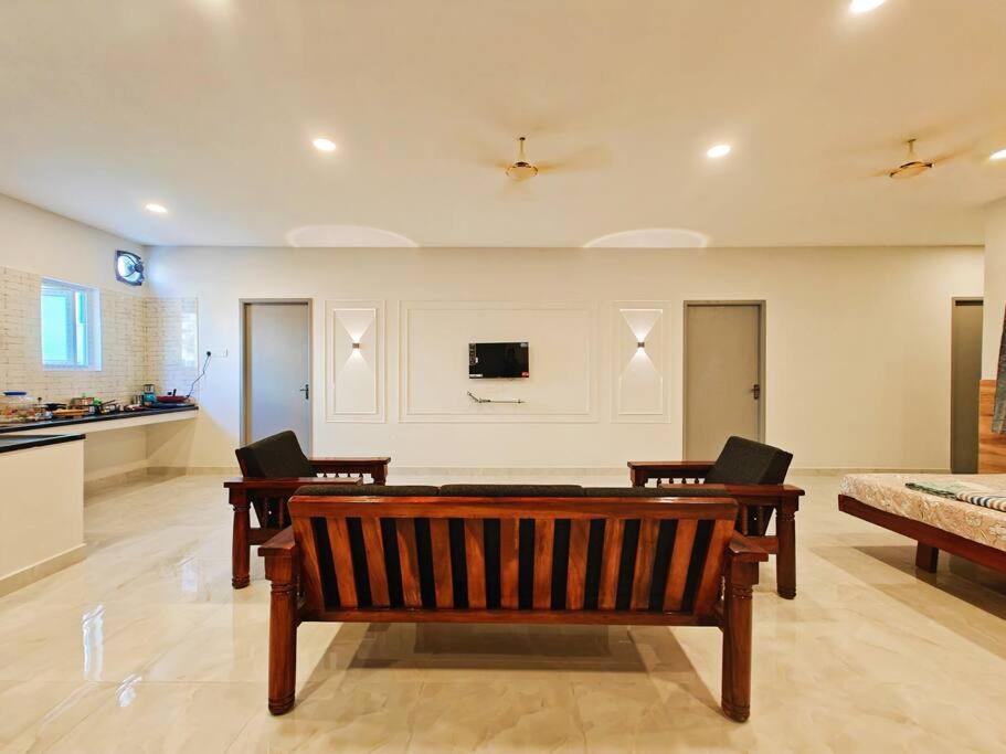 sala de estar con banco y TV en la pared en HOMESTAY - AC 5 BHK NEAR AlRPORT en Chennai