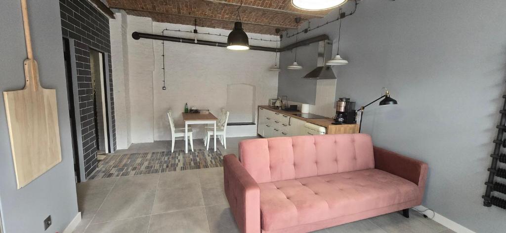 a living room with a pink couch and a kitchen at Apartamenty STARA PIEKARNIA in Płock