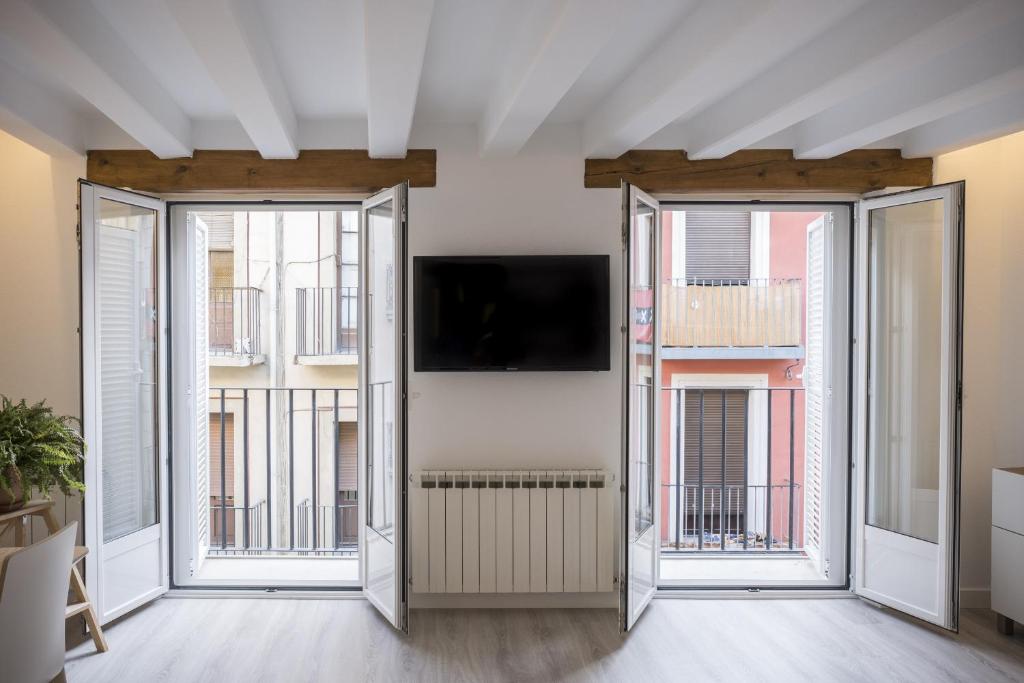 ein Wohnzimmer mit 2 Fenstern und einem Flachbild-TV in der Unterkunft TuApartamento El Mirador de la Estafeta in Pamplona