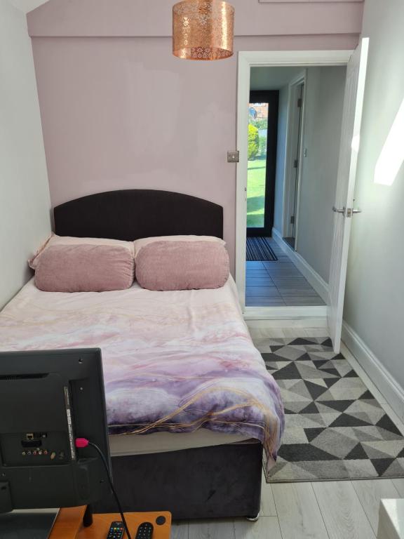 una camera da letto con un letto con cuscini rosa e un tavolo di 1 Bed Annex 2 mins from Harlow Mill train station a Harlow