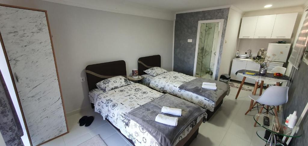 a bedroom with a bed and a table and a kitchen at Cozzy apartment near the Aiport Podgorica in Podgorica