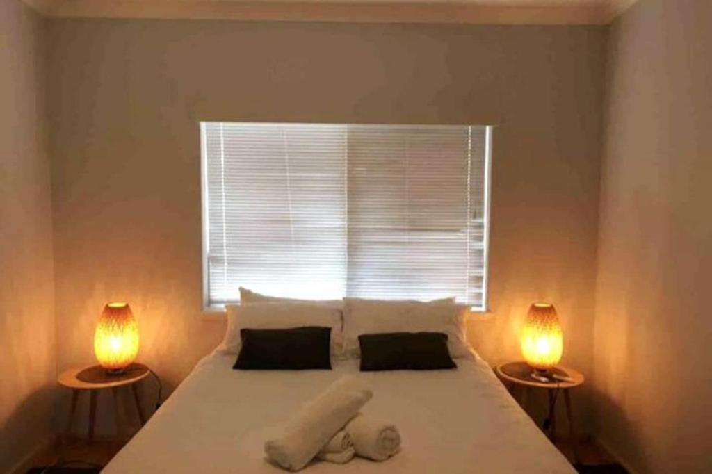 - une chambre avec un grand lit blanc et deux lampes dans l'établissement Acacia Holiday Or Business Stay - Quiet Location, à Perth