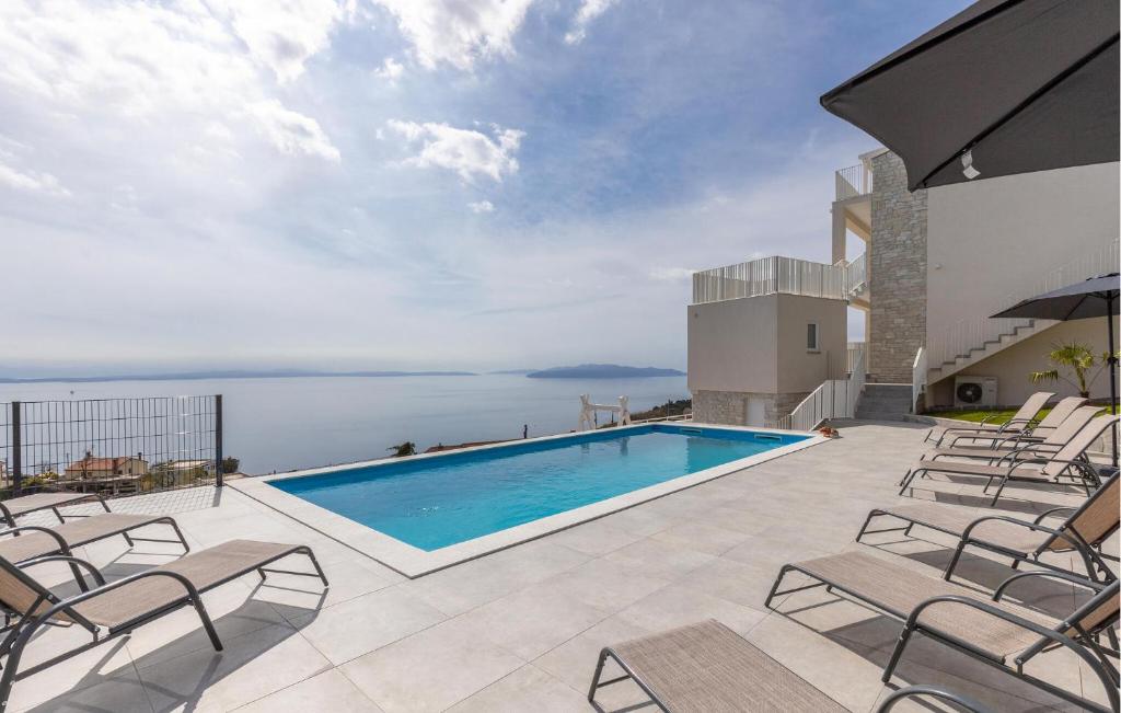 a swimming pool on a patio with chairs and the ocean at Nice Home In Bregi With House Sea View in Breza