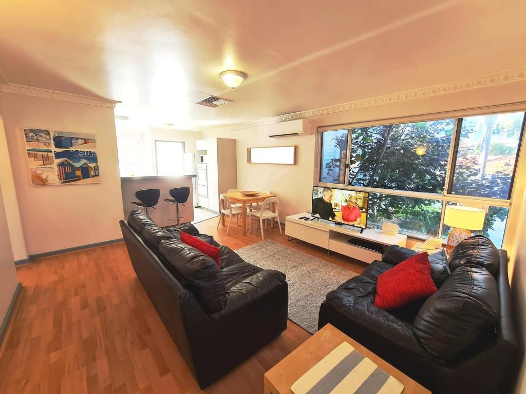 uma sala de estar com dois sofás de couro e uma grande janela em Ocean's "4" Holiday Or Business Stay Accommodation em Perth