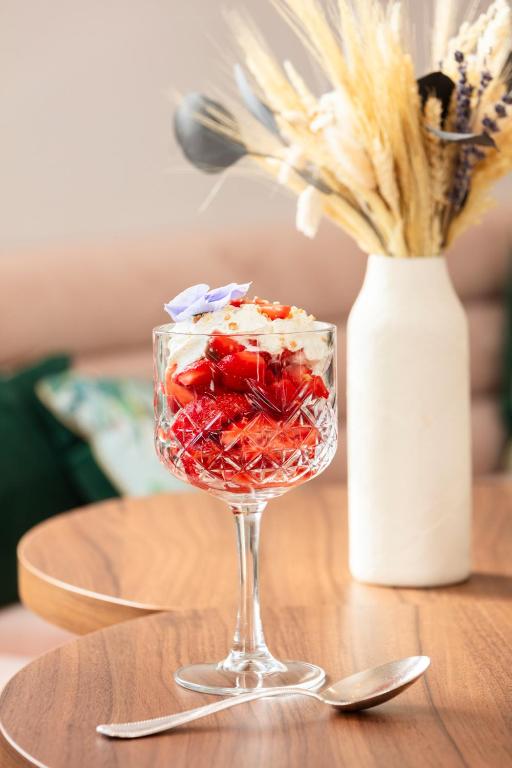 a wine glass with strawberries and a vase on a table at La Bastide Bourrelly - Mathias Dandine in Cabriès