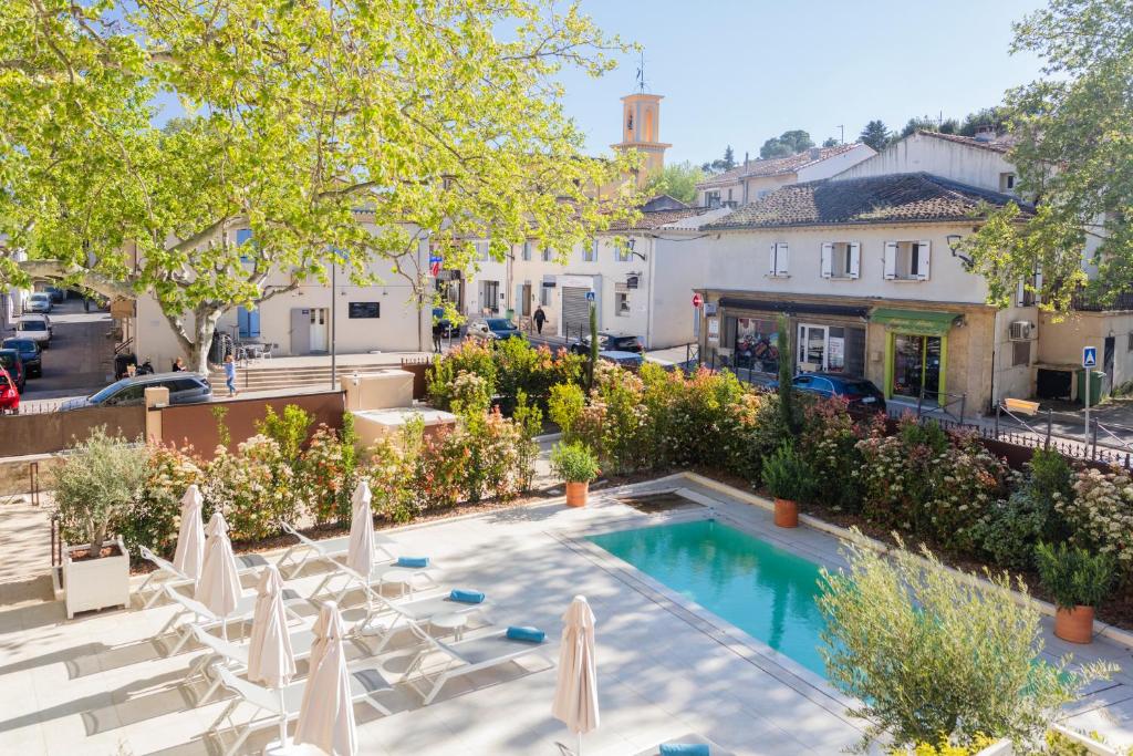 an outdoor swimming pool with chairs and umbrellas at La Bastide Bourrelly - Mathias Dandine in Cabriès