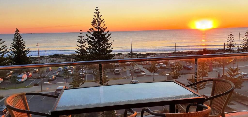 a table and chairs on a balcony with a sunset at The White Pearl Penthouse in Perth