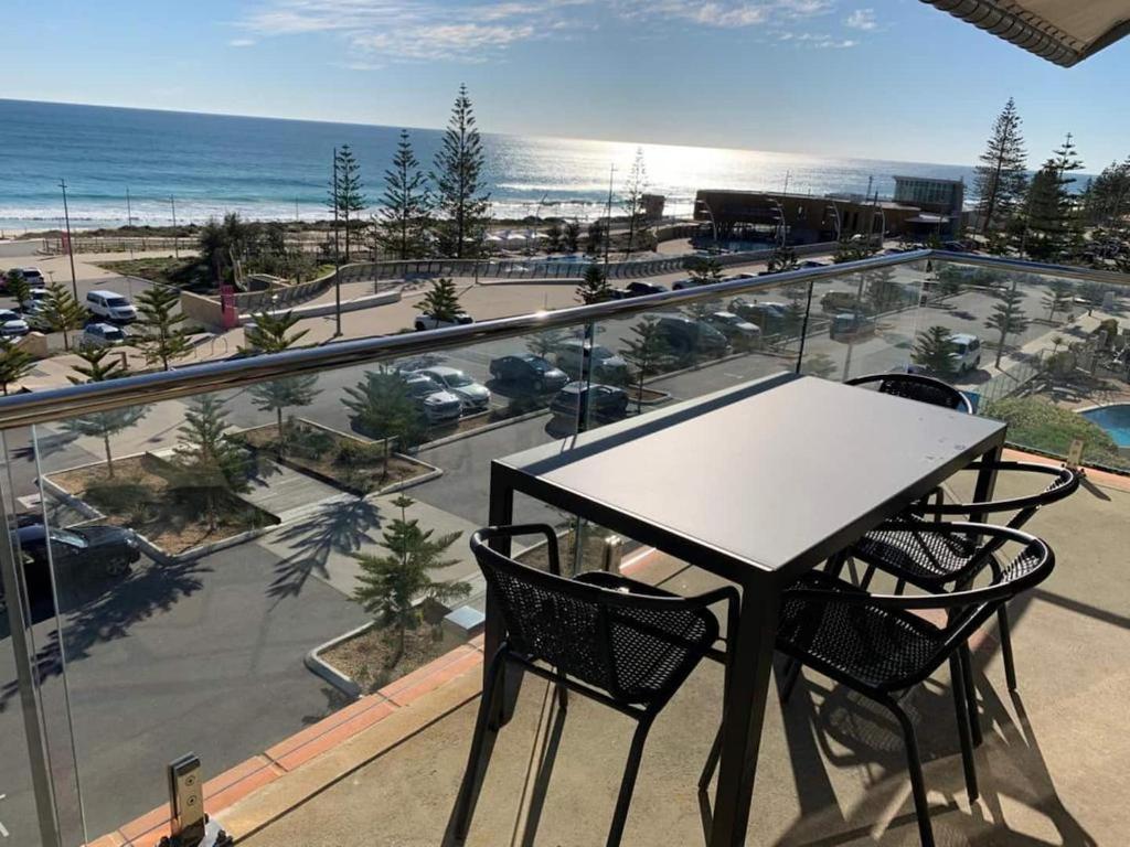 einen Tisch und Stühle auf einem Balkon mit Blick auf den Strand in der Unterkunft The Sea Breeze Penthouse Apartment in Perth