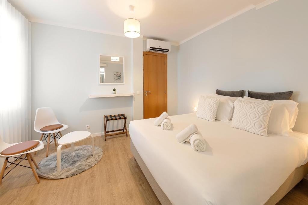 1 dormitorio blanco con 1 cama blanca grande y 2 sillas en Fika Guest House, en Nazaré