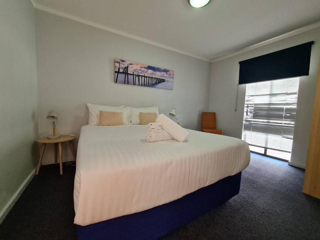 a bedroom with a large white bed and a window at West Beach Lagoon 204 - Ground Floor! in Perth