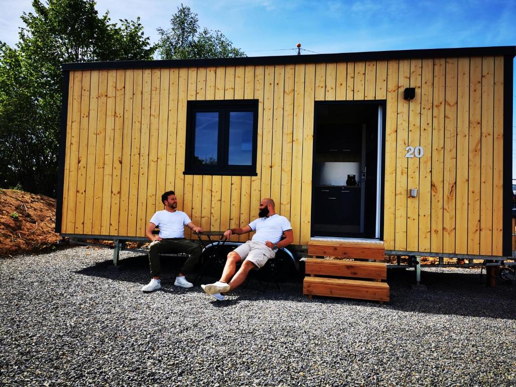 two men sitting on a bench in front of a tiny house at Tiny Guesthouse Herdt Euerbach 