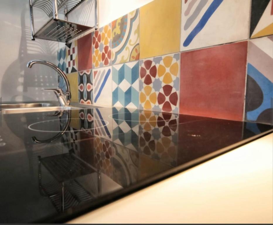 a kitchen with a sink and a colorful tile wall at Mary J Apartment in Trapani