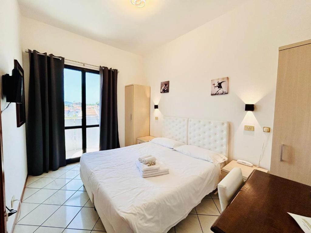 a bedroom with a bed and a table and a window at Hotel Romagna in Cesena