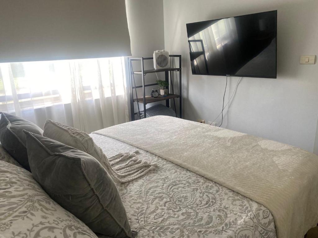 a bedroom with a bed and a flat screen tv at Bonito y acogedor departamento in Los Ángeles