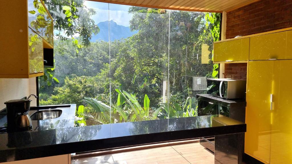 une cuisine avec une grande fenêtre offrant une vue dans l'établissement Chalé 10 até 4 pessoas cozinha próx ao centro, à Itatiaia