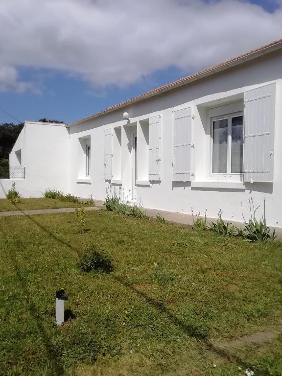 une maison blanche avec des fenêtres à volets blancs et une cour dans l'établissement Maison de vacances La Menou, à Saint-Pierre-dʼOléron
